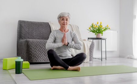 Calm Home Exercises In A Bright Room, A 70-Year-Old Woman Practices Yogaの写真素材