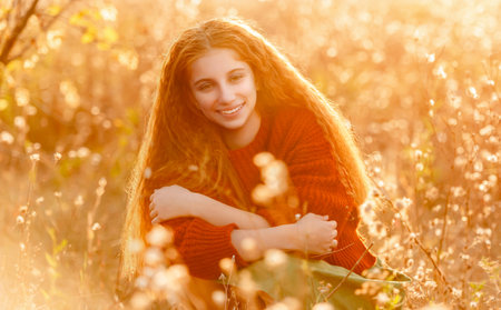 Happy teenage girl walking in autumn nature on yellow tree backgroundの写真素材