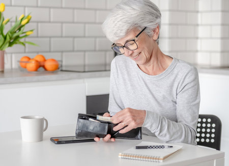 Smiling Elderly Woman Counts Euro Money In Walletの写真素材