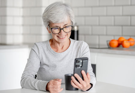 Charming Senora Is Having A Video Call In Kitchenの写真素材