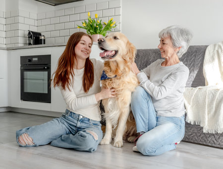 Teenage Girl And Her Grandmother Are At Home With Their Golden Retriever Dogの写真素材