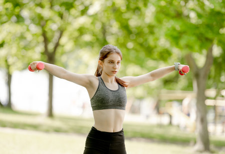 Sporty Girl Exercises With Dumbbell Outdoorsの写真素材