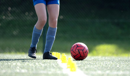 Girl Skillfully Dribbles Ball Between Flip Cups During Football Practice, Close-Up Shotの写真素材