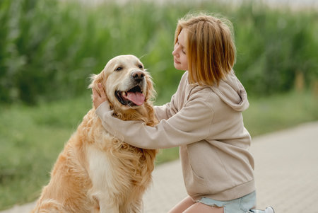 Girl Sits With Golden Retriever On Morning Walkの写真素材