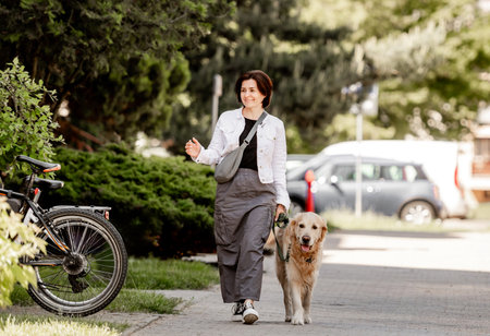 Young Woman With Golden Retriever Enjoys Spring Walkの写真素材
