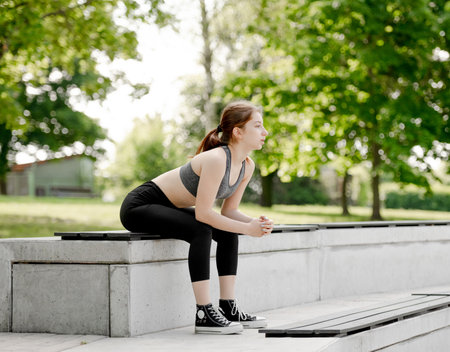 Sporty Girl Catches Her Breath On A Bench After Running In The Parkの写真素材