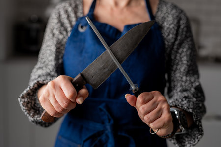 Big Kitchen Knife And Sharpener In Female Hands Are In Close-Up View