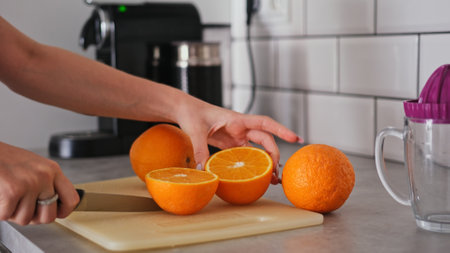 Girl Cuts Orange In Close-Up View In Kitchenの写真素材