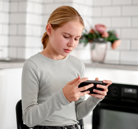 Cute Little Girl Focused While Playing An Online Game On Smartphoneの写真素材
