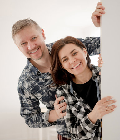 Couple Peeking Out From Behind The Door At Homeの写真素材