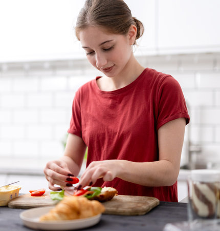 Young Girl Makes Breakfast In The Kitchen At Homeの写真素材