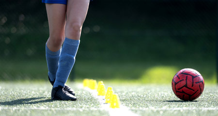 Girl Skillfully Dribbles Ball Between Flip Cups During Football Practice, Close-Up Shot