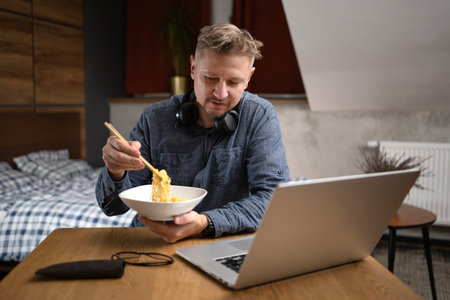 Man Eating Dinner At Laptop At Homeの写真素材