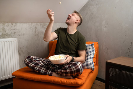 Man Playing With Popcorn At Home In A Chairの写真素材