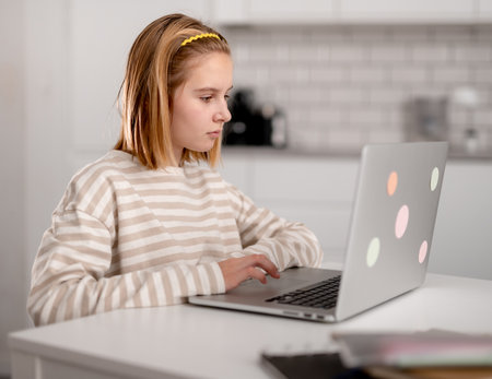 Cute Little Girl Using A Laptop At Home And Browsing The Internet And Social Mediaの写真素材