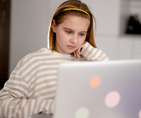 Cute Little Girl Using A Laptop At Home To Surf The Internet And Social Mediaの写真素材
