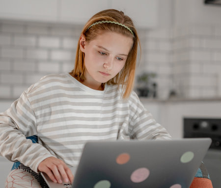 Cute Little Girl Uses A Laptop At Home To Surf The Internet, Watch Movies, And Feed On Social Mediaの写真素材