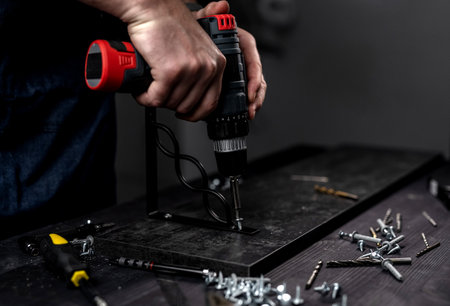 Man Screws Bracket To Shelf With Screwdriver, Hands In Close-Upの写真素材