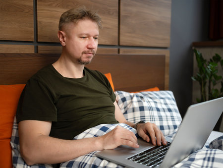Man Watching News On Laptop In The Morning In Bedの写真素材