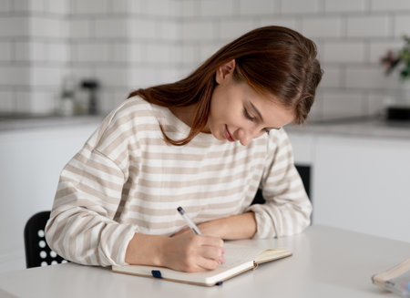 Happy Girl Doing Homework At Home At The Tableの写真素材