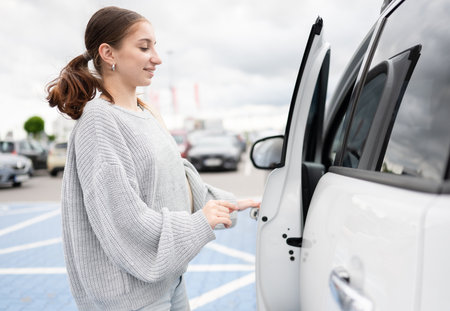Young Woman Opening Car Door In The Parking Lotの写真素材