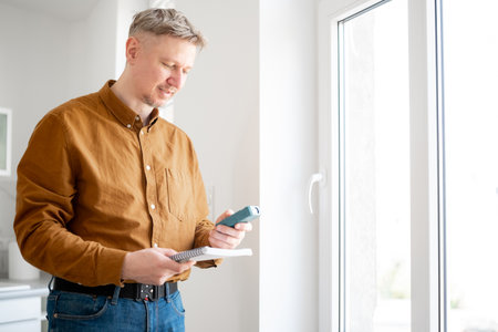 Happy Man Measures The Window Opening With A Special Device And Records The Measurementsの写真素材