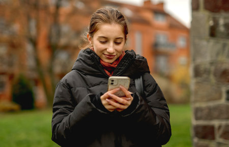 Smiling Girl Holding A Smartphone Against A Blurred City Background In Spring