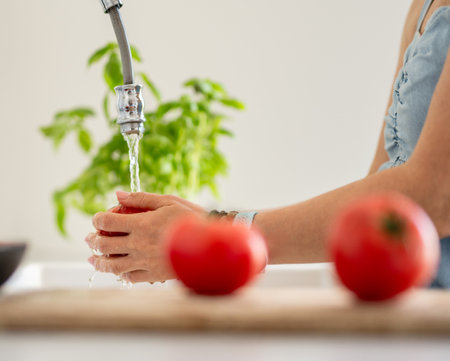 Close-Up Of Woman's Hands Washing A Tomatoの写真素材
