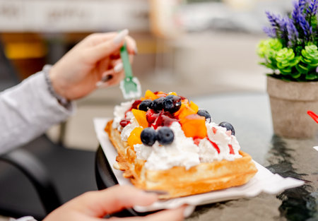 Close-Up Of A Girl Holding Belgian Waffles With Fruit In A Cafe Soft Focusの写真素材