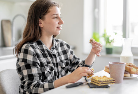 Happy Teen Girl Eating Pie At Home In The Kitchenの写真素材