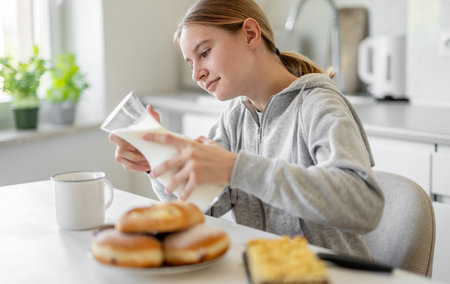 Sweet Teenage Girl Drinking Milk At Breakfast At Home In The Kitchenの写真素材