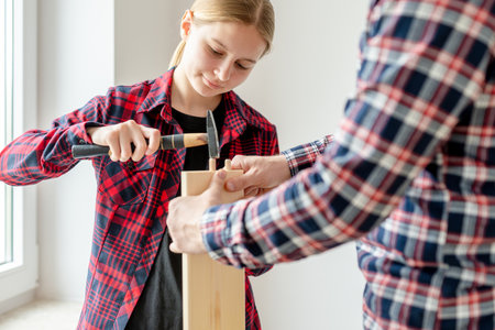 Girl And Dad Assemble Furniture By Hammering Pegs Into A Boardの写真素材