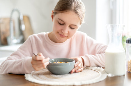 Happy Teen Girl Eating Dry Breakfast In The Kitchen At Homeの写真素材