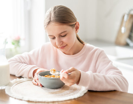 Happy Teen Girl Eating Dry Breakfast In The Kitchen At Home