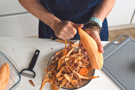 Woman Peeling A Raw Sweet Potato In A Closeup Top-Down Viewの写真素材
