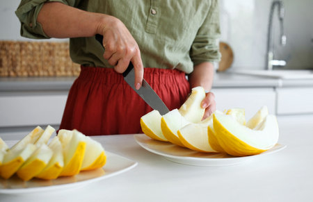 Woman Cutting Melon Into Pieces In The Kitchen Close-Upの写真素材