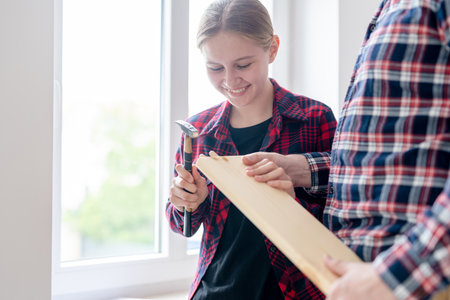 Girl And Dad Assemble Furniture By Hammering Pegs Into A Boardの写真素材