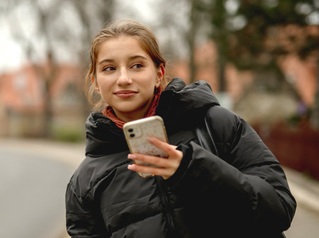 Sweet Girl With Smartphone Against A Backdrop Of A Cityの写真素材