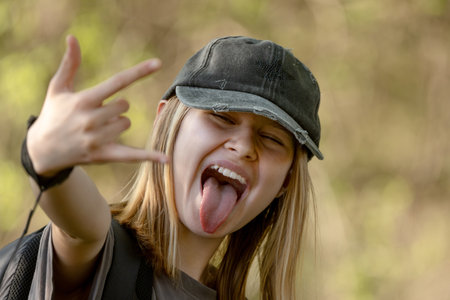 Fun Cool Teen Girl Sticking Out Tongue Against A Blurred Backgroundの写真素材