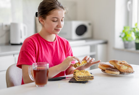 Happy Teen Girl Eating Pie At Home In The Kitchenの写真素材