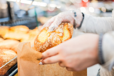 Girl Putting A Bun In A Bag In The Supermarket Bakery Section With Hands In Close-Up