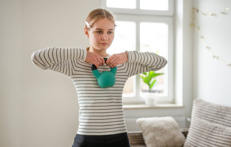 Girl Doing Exercise With Kettlebell At Home In The Living Room