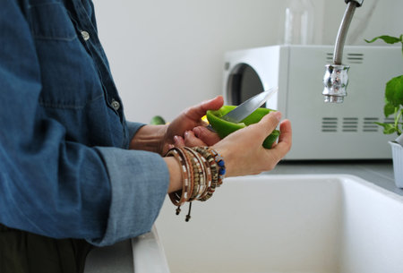 Woman Cleaning A Green Bell Pepper Over A Sink