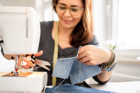 Woman Sewing At Home On A Sewing Machine And Cuts The Thread
