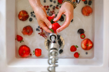 View From Above Of Woman Washing Strawberries Over Sink, Hands Close-Up