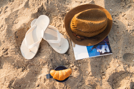 lying on the sand hat, flip flops, magazine, coffee, croissantの写真素材