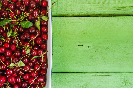 Juicy fresh cherries on a bright wooden background.