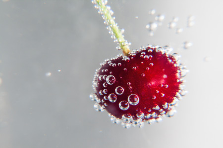 Cherry in water with bubbles.の写真素材
