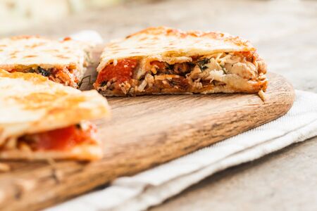 pile of quesadillas with chicken and vegetables on the rustic board.