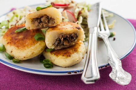 fried potato pies with mushrooms and salad on a plate.